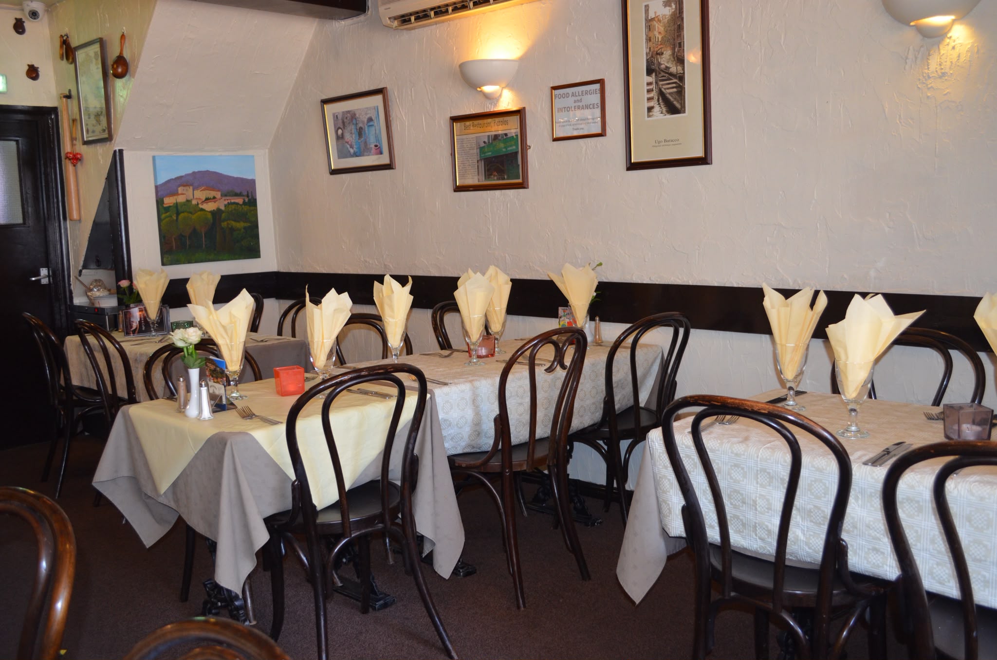 Tables set with folded napkins and fresh flowers in the Piccolos dining room