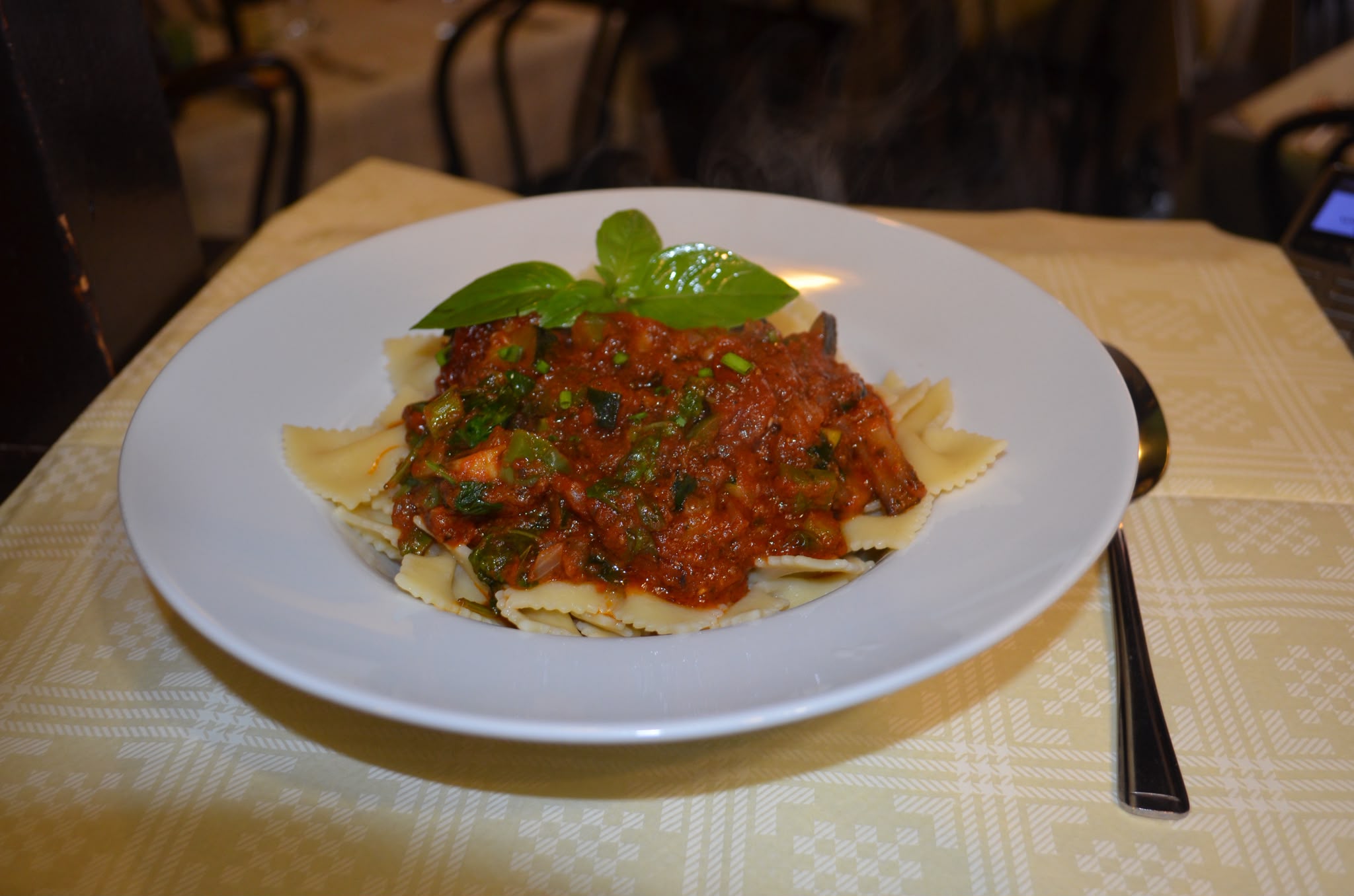 Farfalle pasta topped with a rich tomato and vegetable ragù, garnished with fresh basil